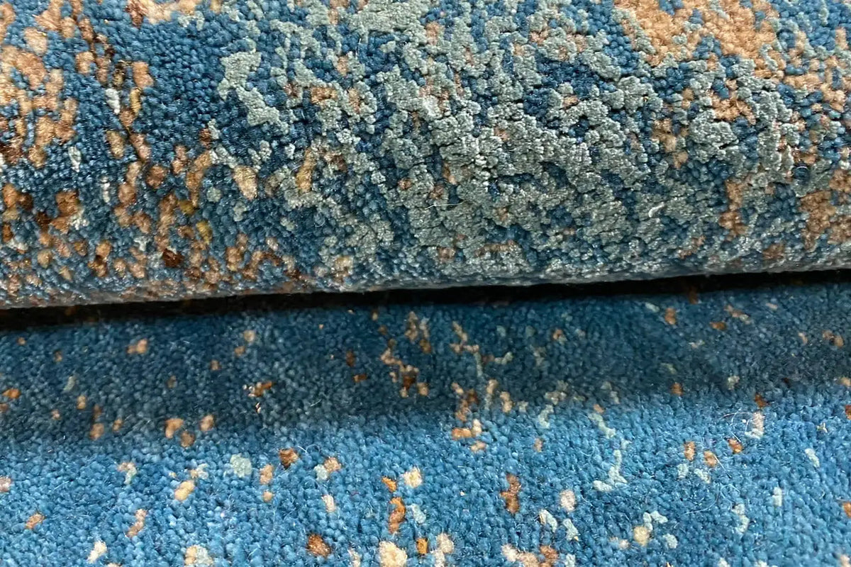 Designer rug close-up: blue pile, golden-brown accents, visible texture
