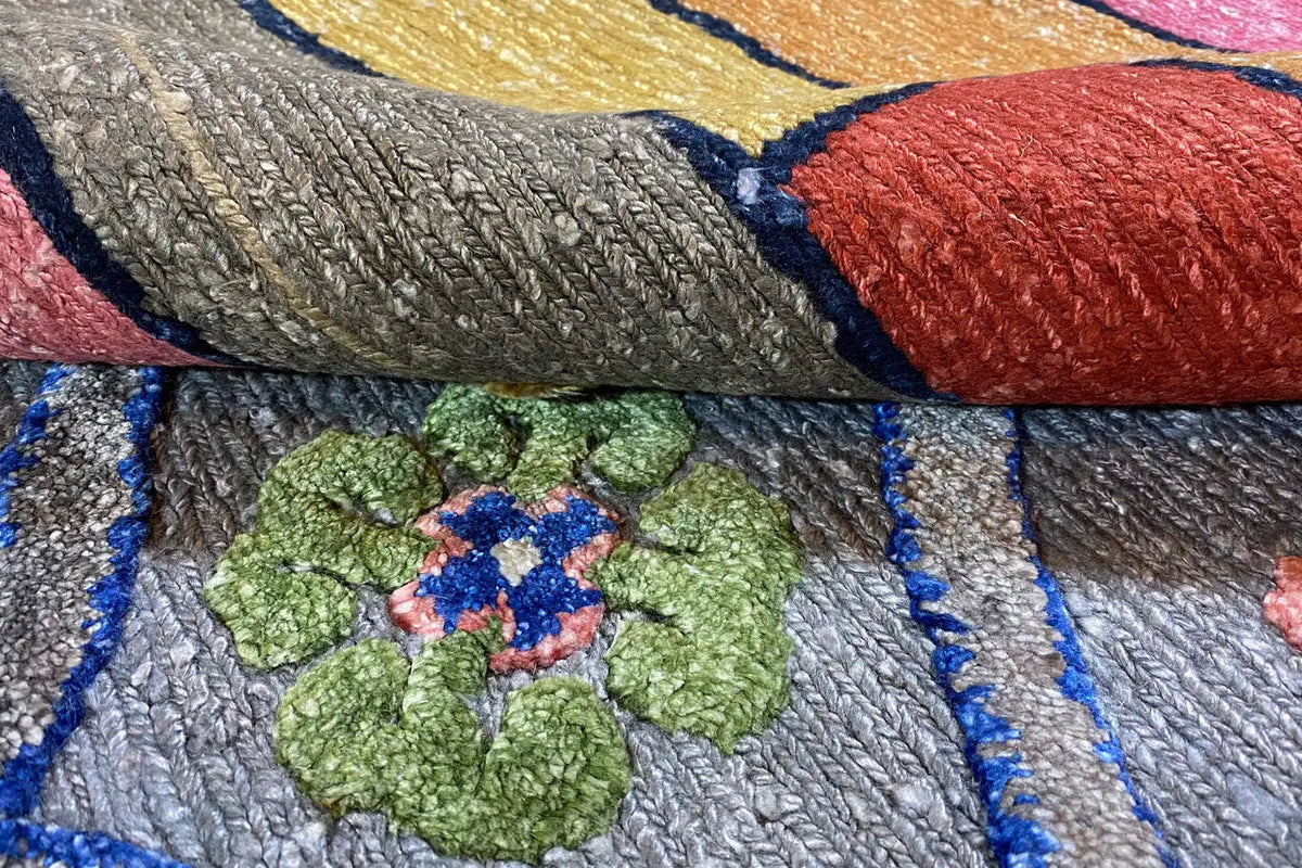 Rug detail with a braided texture, blue border, and floral ornament