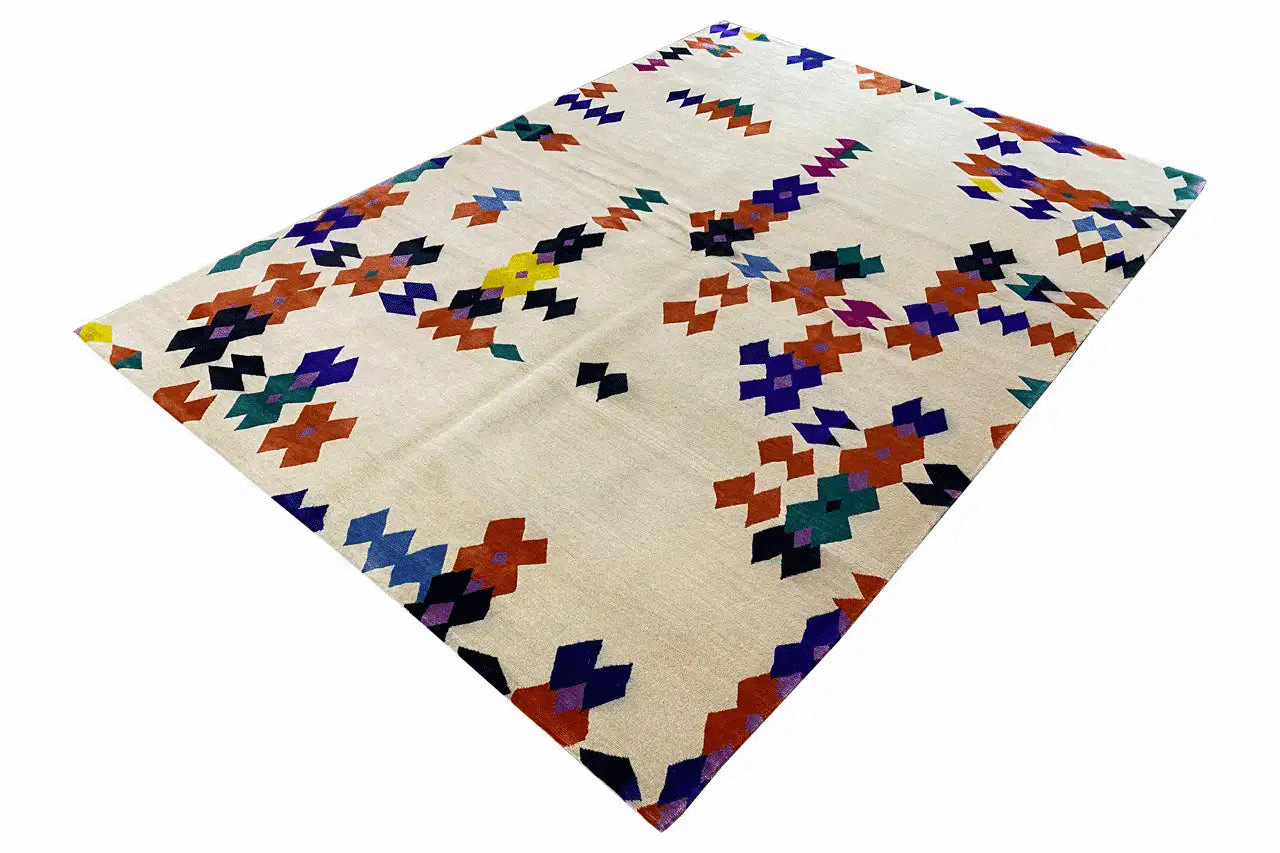 Rug with a geometric pattern in blue, red, green, and purple on a light background, at an angle.