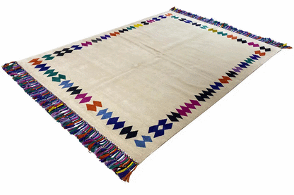 Rug with fringes, beige base, and colorful zigzag border decoration
