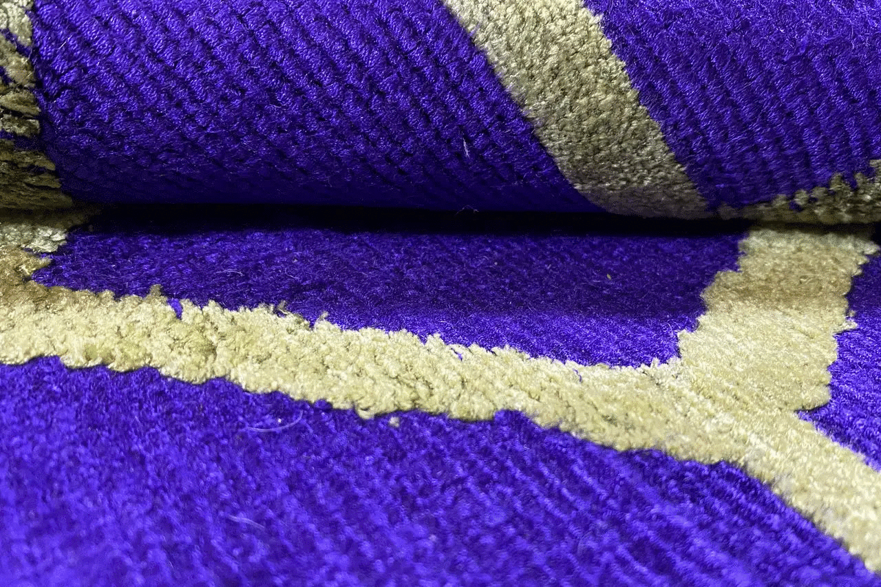 Carpet fiber detail with a purple surface and yellow-green contrasting lines in the pattern
