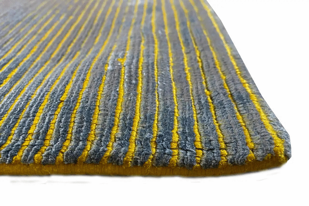 Blue-gray designer rug with yellow lines, short pile, and a straight edge
