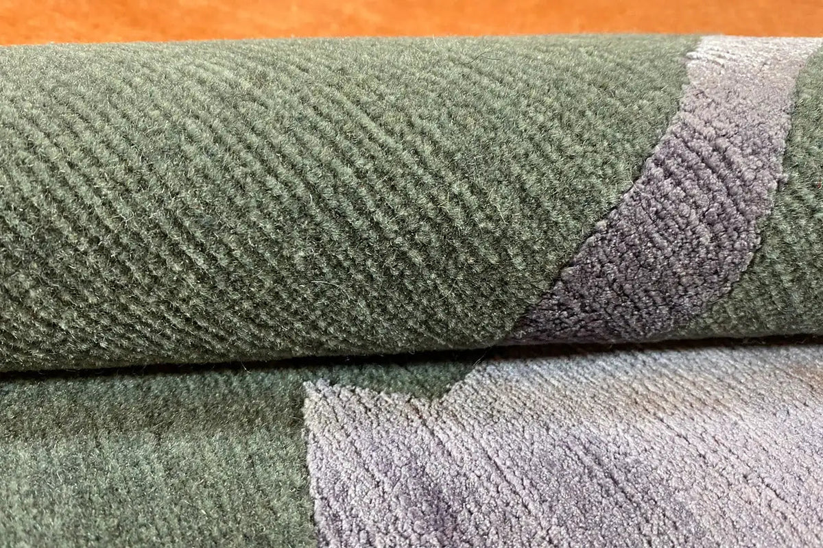 Close-up of carpet edge: dense pile in a greenish and purple-green color combination