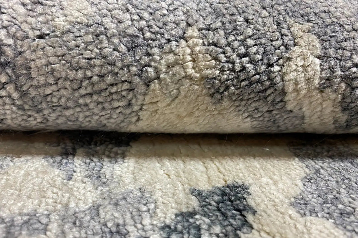 Designer rug close-up: short, soft pile texture in gray-beige with blue flecks