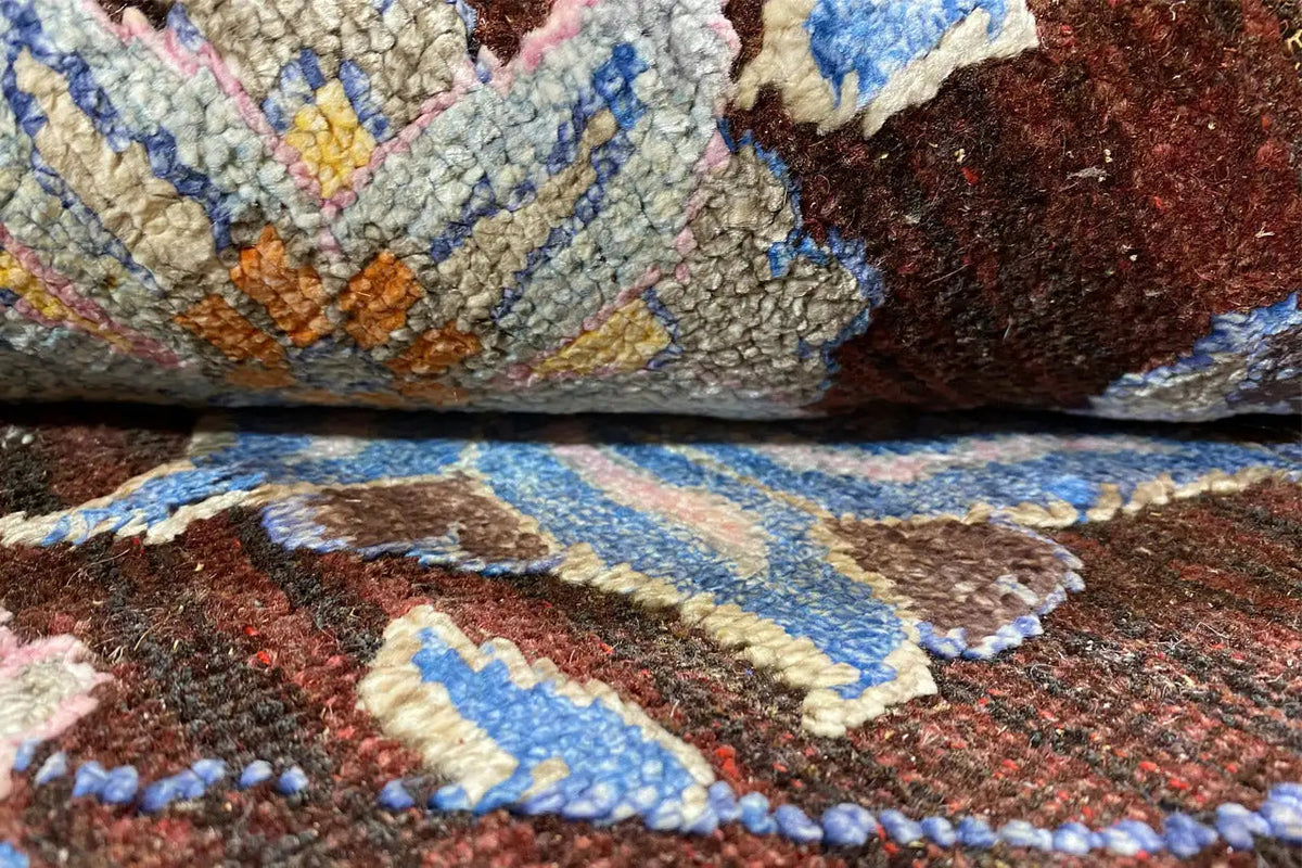 Carpet detail with a high-pile texture, blue and yellow floral ornament on a brown background