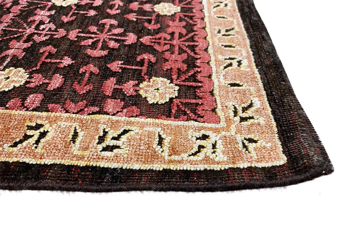 Rug with a patterned border in dark burgundy, beige, and black