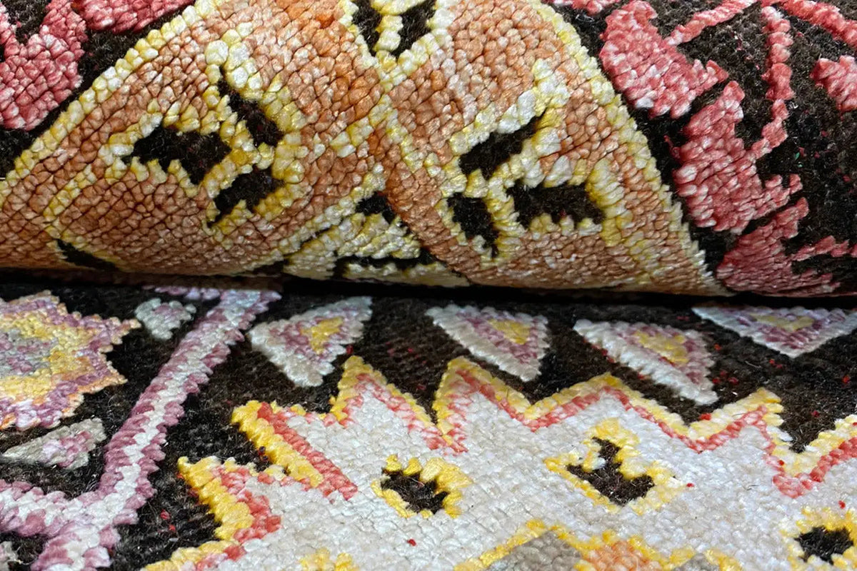 Carpet detail with a dense pile pattern in brown, pink, and dark gold