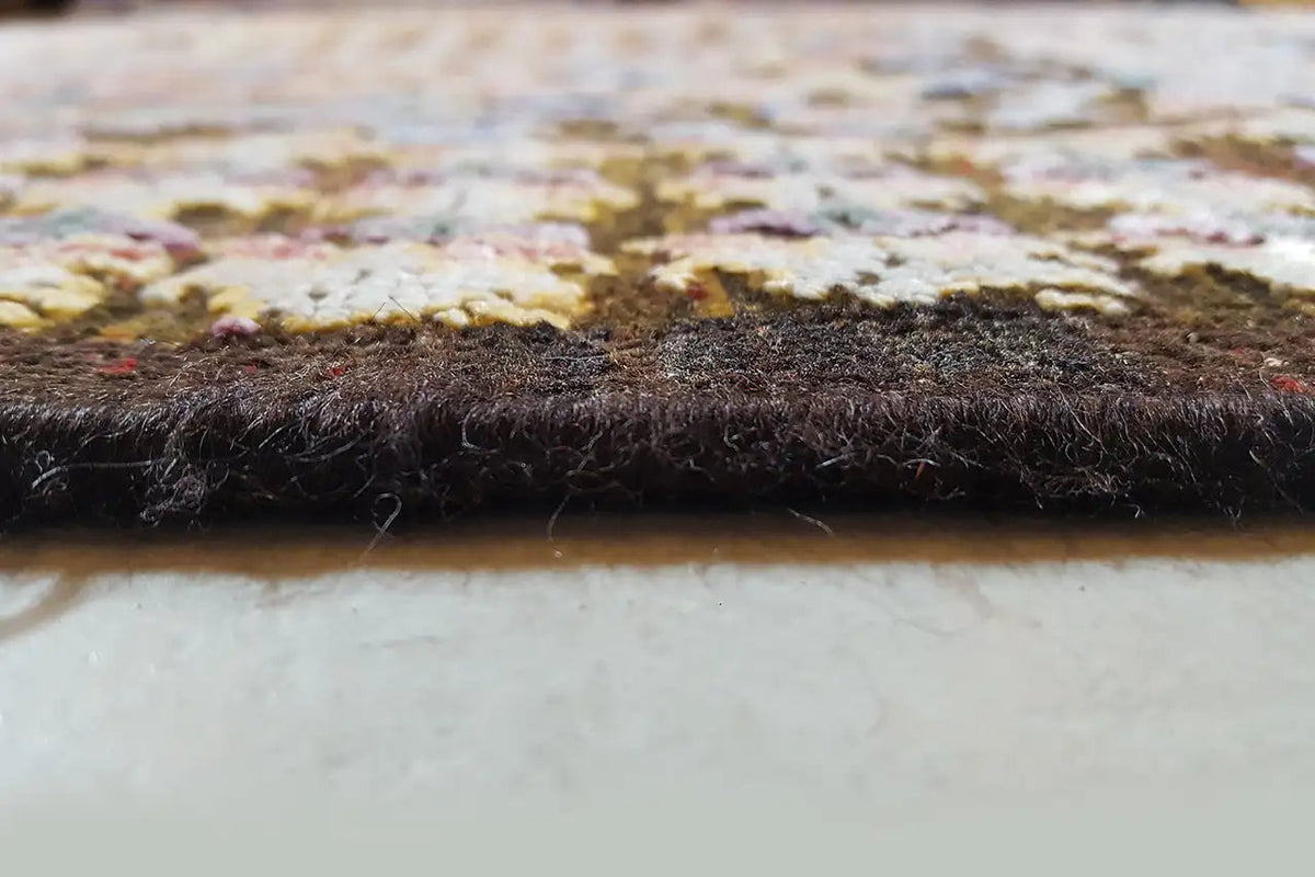Rug edge with a dense pile and dark underside, multicolored pile on top.