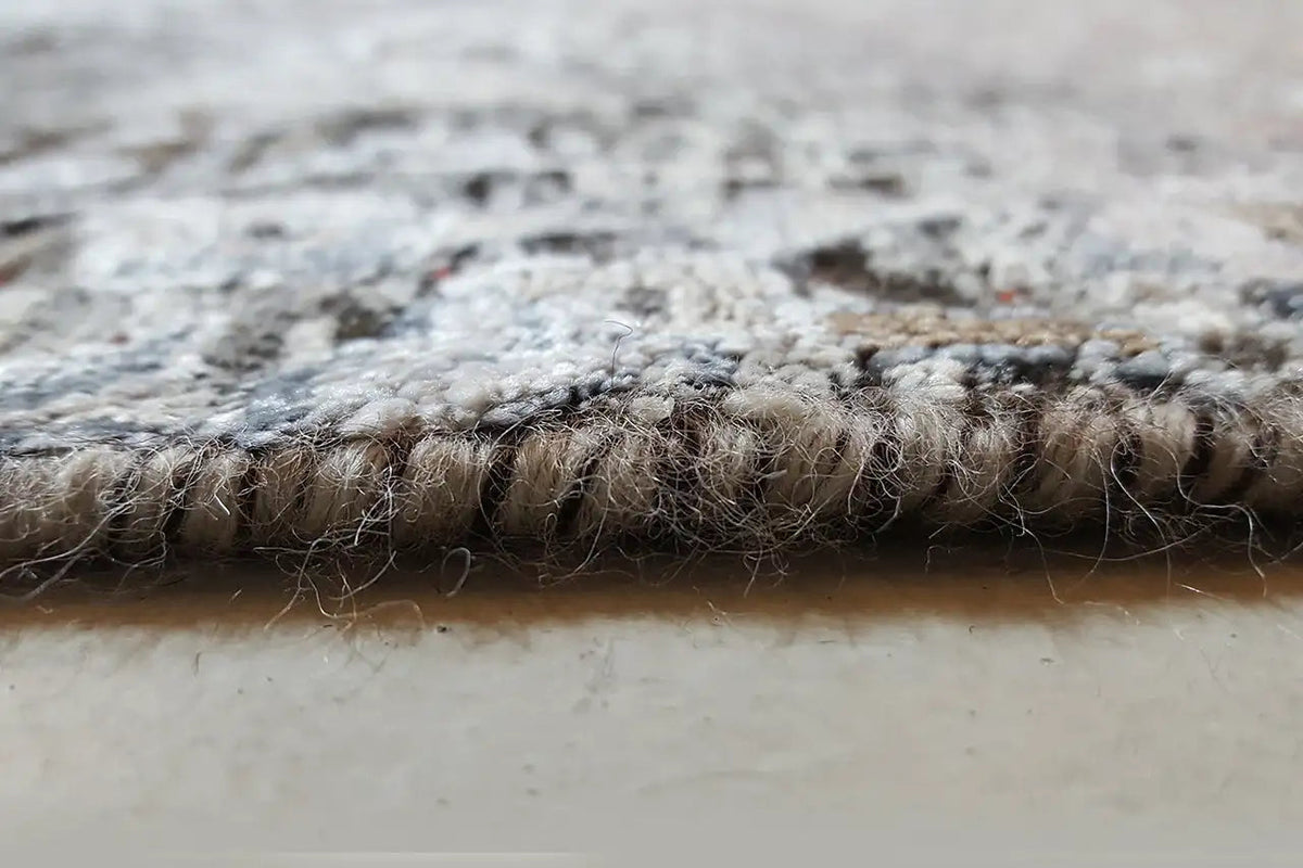 Carpet edge in detail: woven pile and crimped lower edge, gray