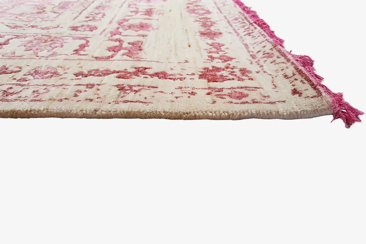 Rug edge from the side: fringe and underside at the edge, cream/pink pattern