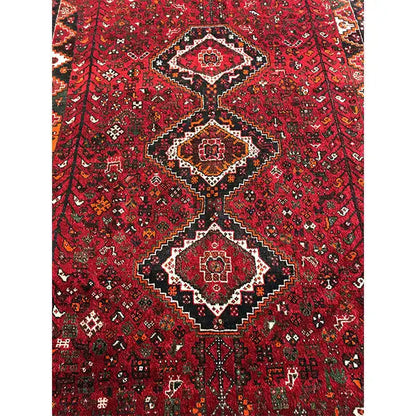 Red Oriental rug with central medallions and a dense black-and-cream pattern