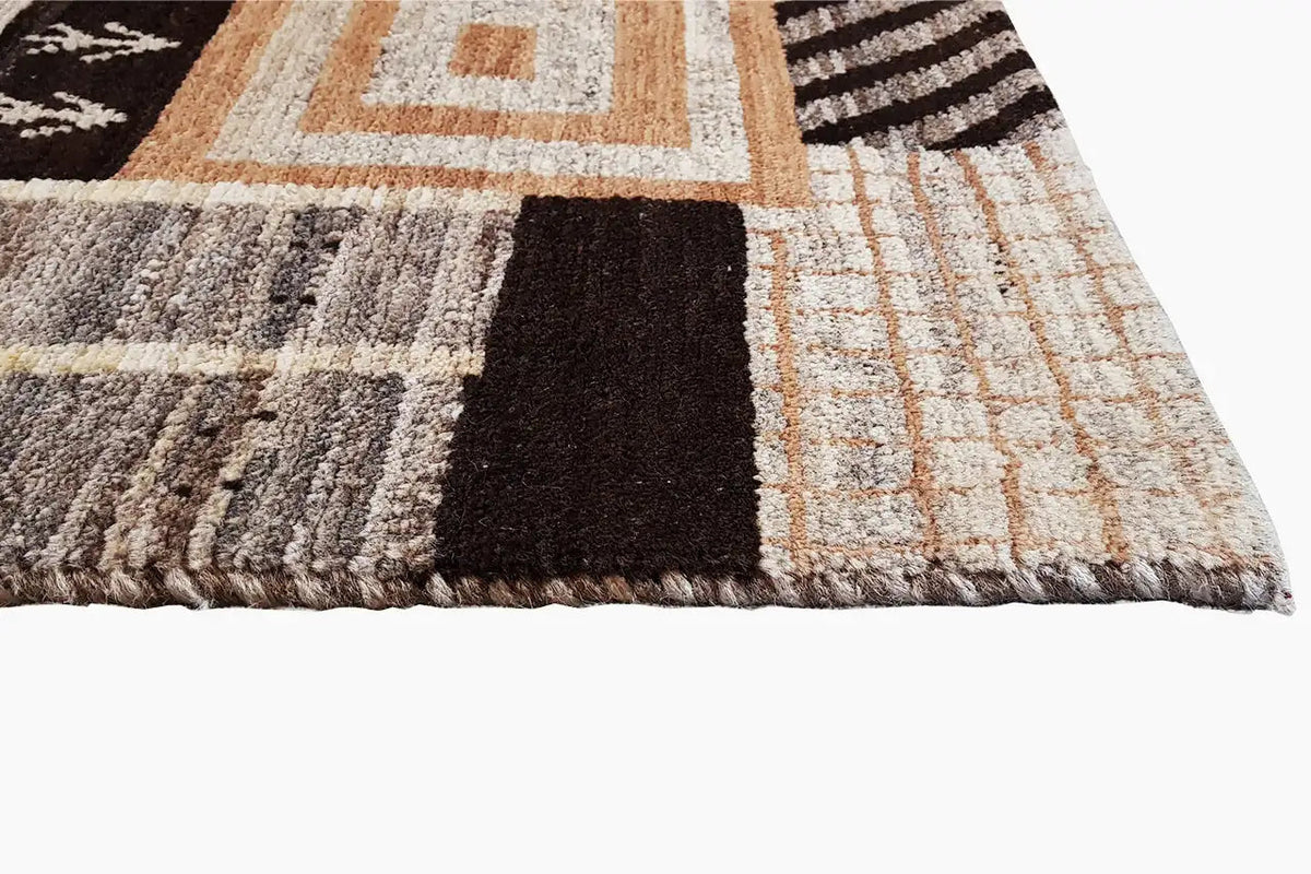 Rug edge with fringe and a multicolored geometric pattern in brown, beige, and black