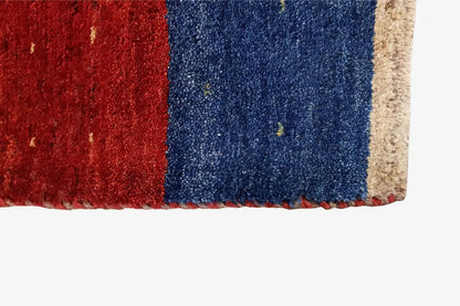 Gabbeh rug corner with red and blue pile and a beige border, rectangular.