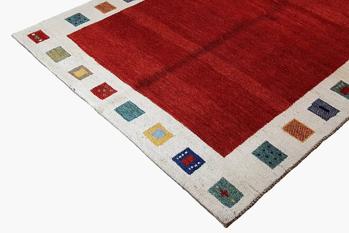 Red Gabbeh rug with a cream-colored border and multicolored square motifs along the edge