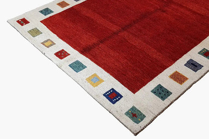 Red Gabbeh rug with a cream-colored border and multicolored square motifs along the edge