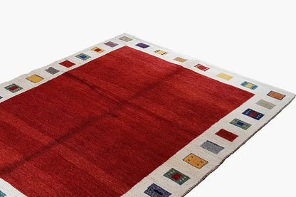 Gabbeh rug with a red center and cream-colored border, decorated with colorful squares
