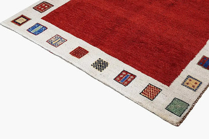 Gabbeh rug: red pile, beige border with colorful square patterns, close-up of the corner