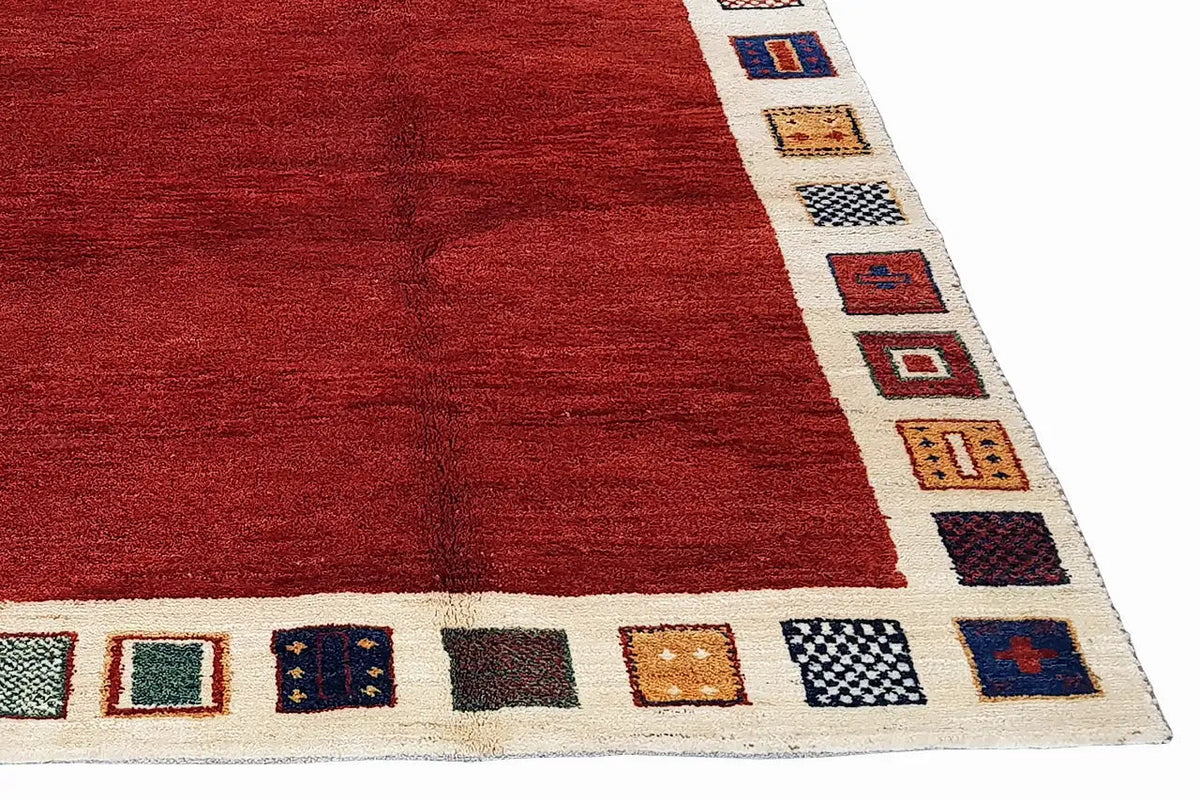 Rug with a red geometric field pattern and a beige border featuring small colorful squares