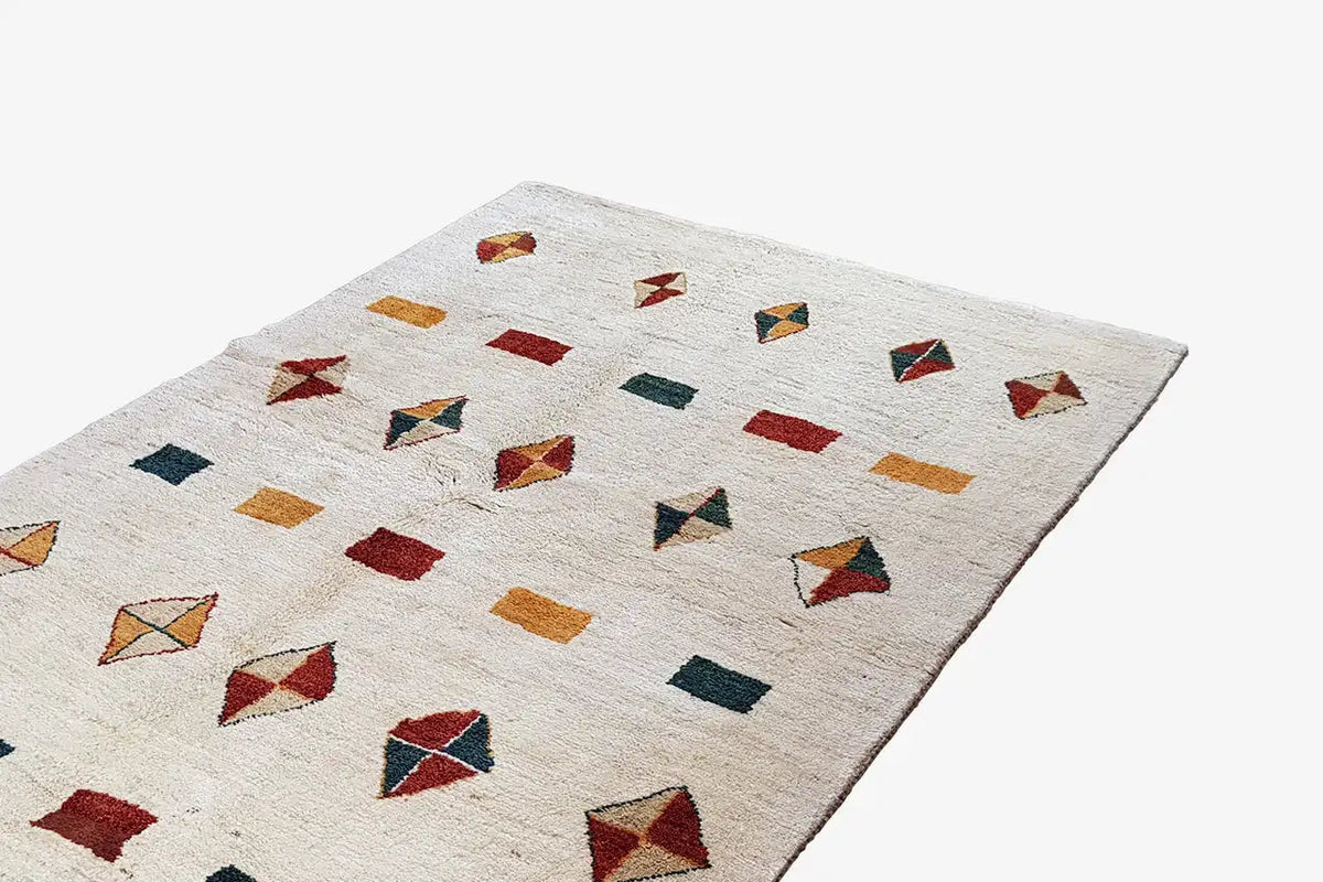 Gabbeh rug with color squares and diamonds in red, green, and ochre on a light background