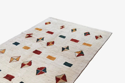 Gabbeh rug with color squares and diamonds in red, green, and ochre on a light background