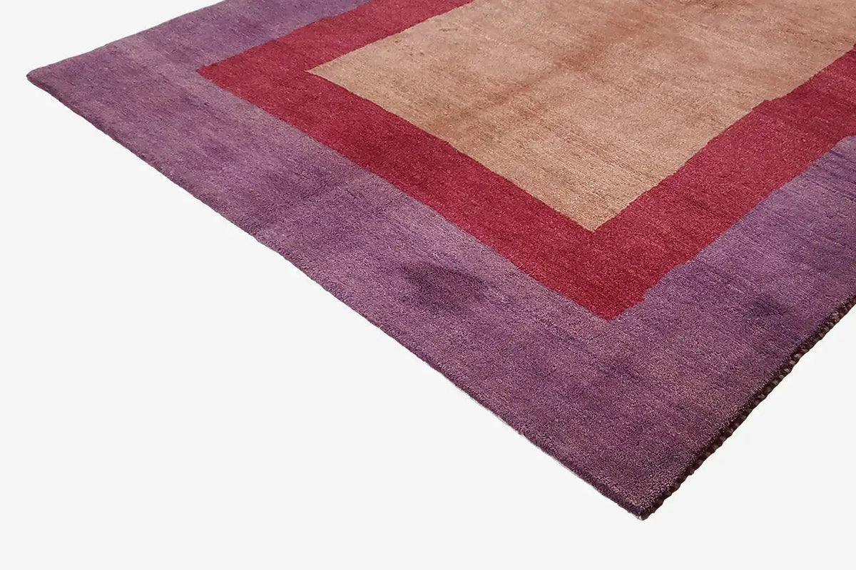 Close-up of Gabbeh rug: purple pile with a red square border and beige center.