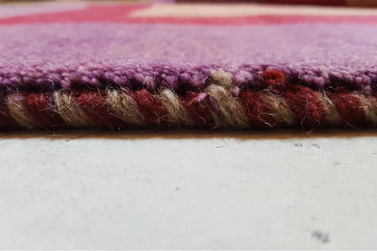 Gabbeh rug edge view: dense pile with a purple and burgundy edge finish.