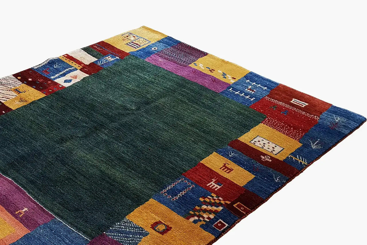 Gabbeh rug with a dark green field and rectangular patchwork borders in blue/red