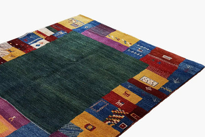 Gabbeh rug with a dark green field and rectangular patchwork borders in blue/red