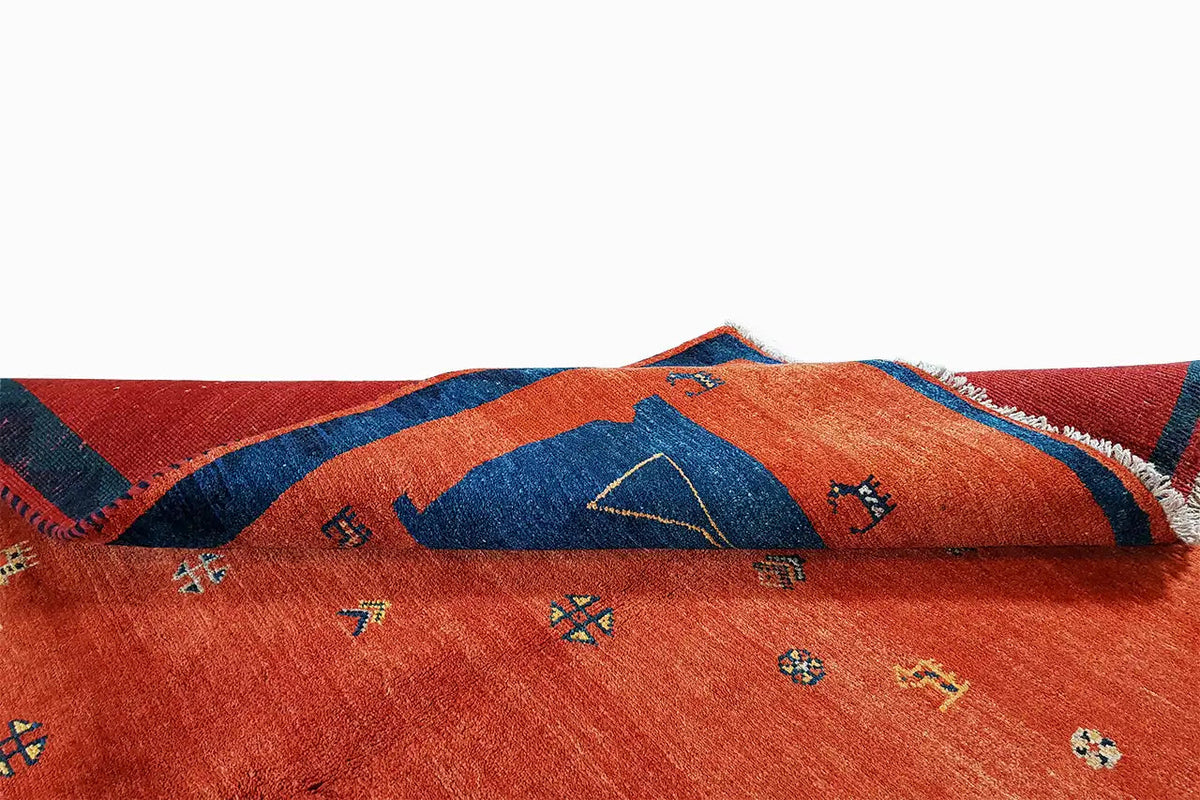 Red Gabbeh rug with a blue border and colorful geometric patterns, with fringes