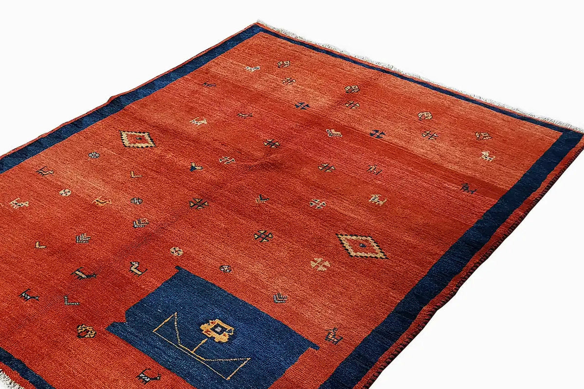 Red rug with a blue decorative panel and colorful geometric patterns, with fringes