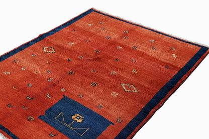 Red rug with a blue decorative panel and colorful geometric patterns, with fringes