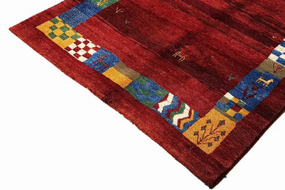Gabbeh rug: red grid with multicolored block and elephant motifs along the edge