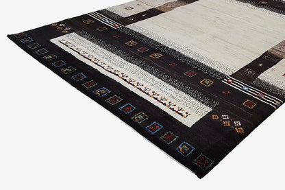 Gabbeh rug viewed from above at an angle: black-and-beige central area with colorful decorative elements