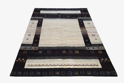 Gabbeh rug in triangular view: black outer frame, beige surface with decorative border