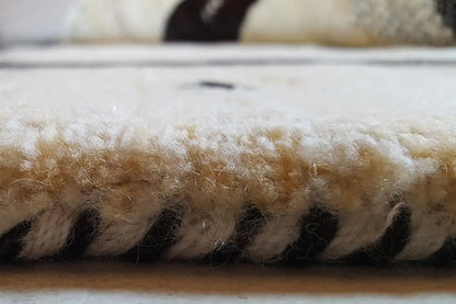Detail of the carpet edge: dense pile with black-and-beige color distribution and a fine texture
