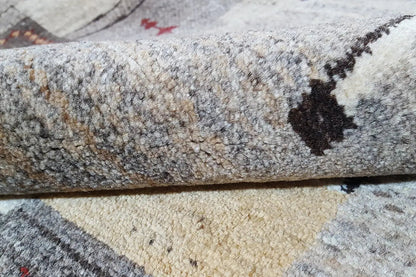 Detailed view of a Gabbeh rug: textured pile surface with a pattern in gray, cream, and dark brown