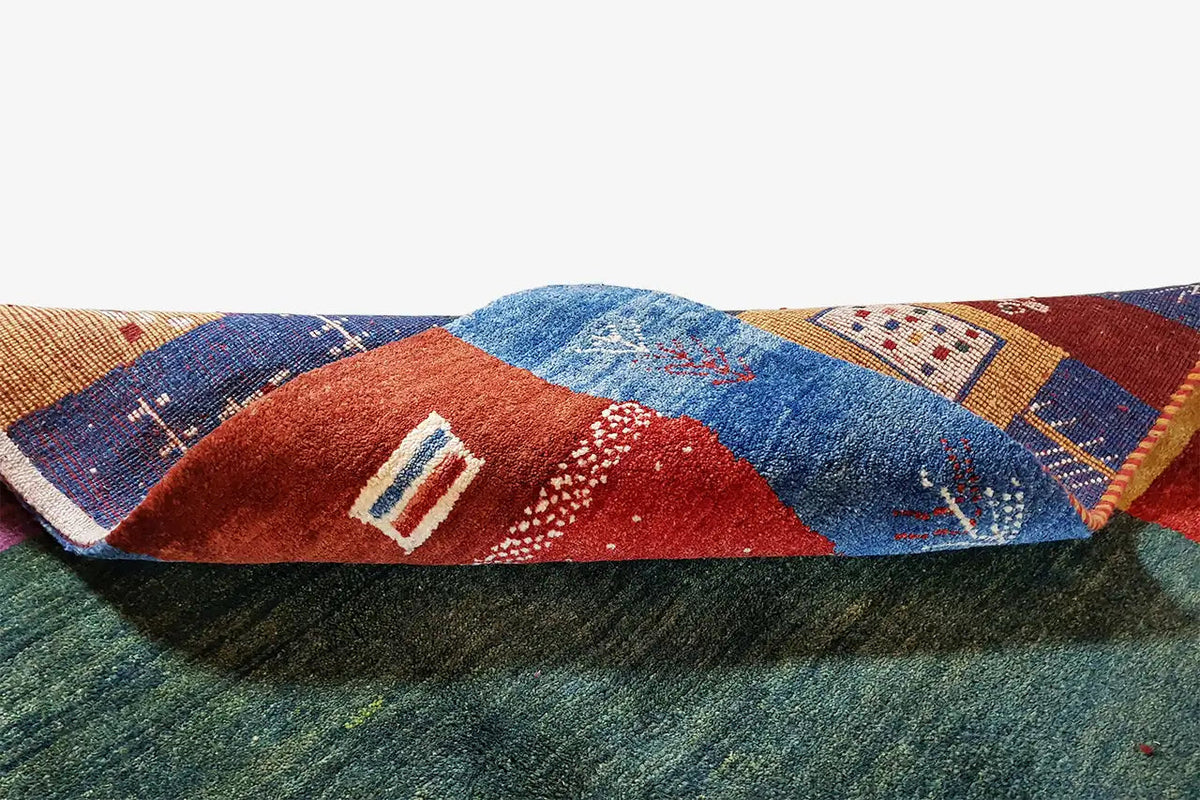 Gabbeh rug corner: dark green pile area with red and blue patchwork motifs