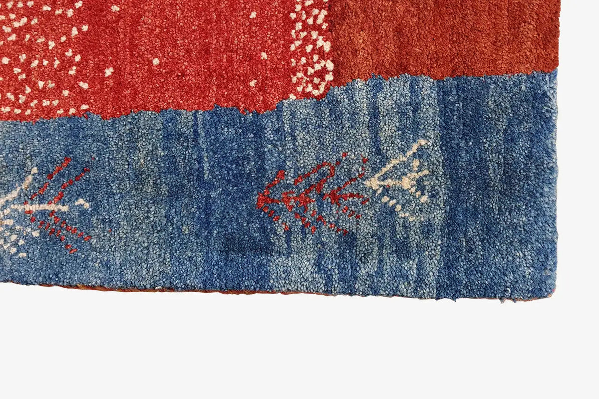 Gabbeh rug border: red-and-blue section with embroidered star/arrow ornaments