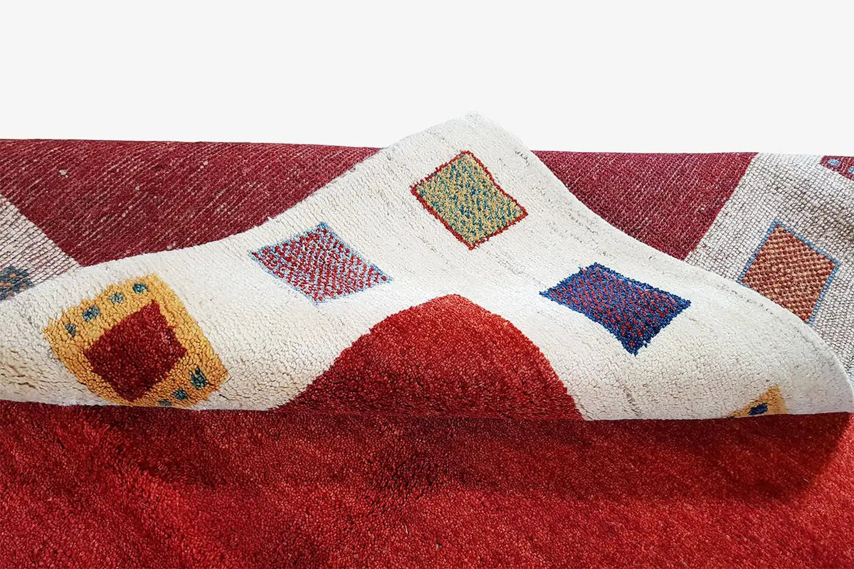 Gabbeh rug with colorful diamonds and squares in a red and cream-colored border area