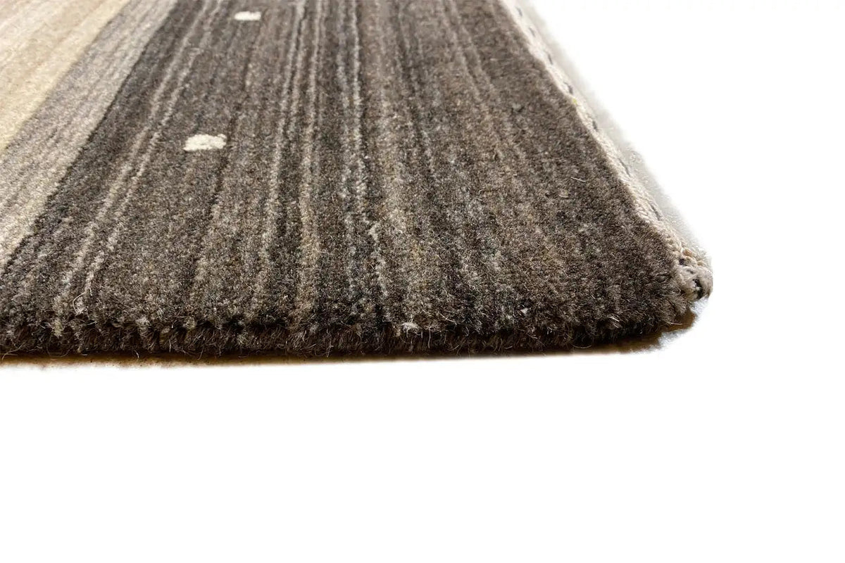 Rug edge with a dark, mottled surface and fine gray/beige stripes