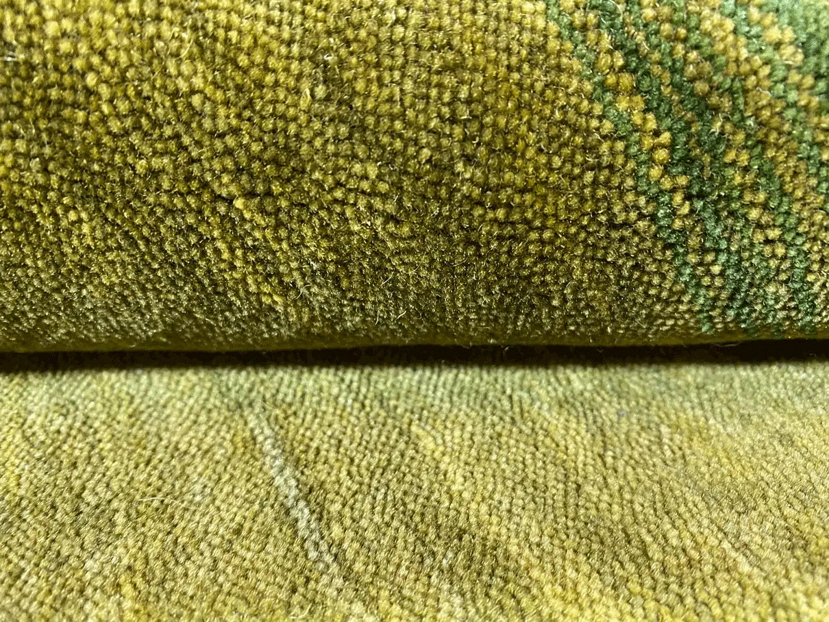 Close-up of a Gabbeh rug: dense pile with a mottled green-yellow texture