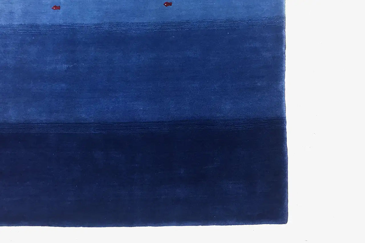 Blue Gabbeh rug in detail: stripe pattern at the top, individual red and white dots