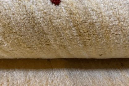 Gabbeh rug: Detail of the light beige wool pile with a small red accent