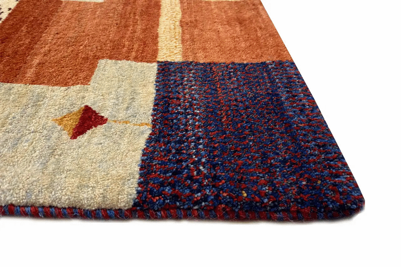 Corner view of a patchwork rug with a hand-knotted pile and bound edge