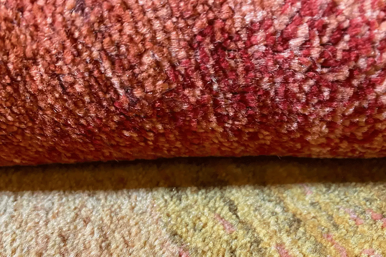 Close-up: textured wool rug with a mottled pile surface in reddish brown and beige