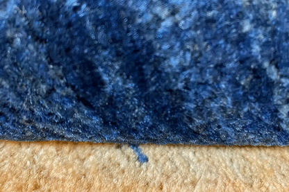 Blue carpet pile with a contrasting beige edge, fine texture visible