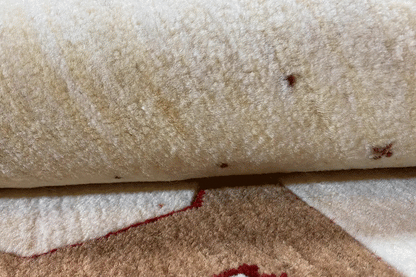 Gabbeh rug detail: light wool texture with reddish-brown patches and fine speckles