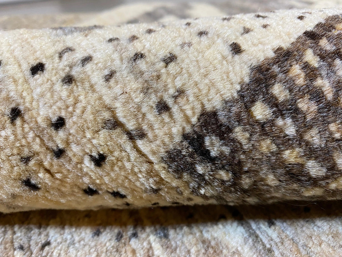 Close-up of the carpet pile: beige wool fabric with dark spots and stripes
