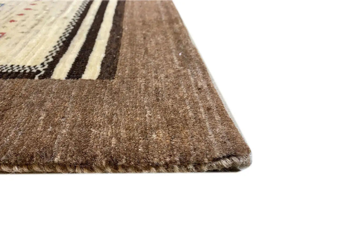 Gabbeh rug corner with brown pile and beige decorative stripes along the edge