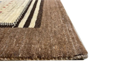 Gabbeh rug corner with brown pile and beige decorative stripes along the edge